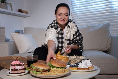 Happy overweight woman with unhealthy food at home