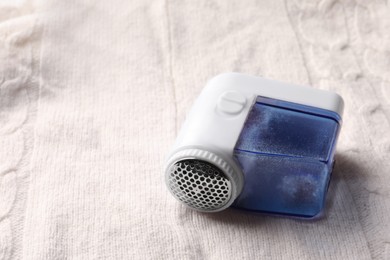 Photo of Fabric shaver with fuzz on knitted cloth, closeup. Space for text