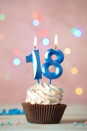18th birthday. Delicious cupcake with number shaped candles for coming of age party on white table