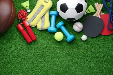 Set of different colorful sports equipment on green grass, flat lay. Space for text