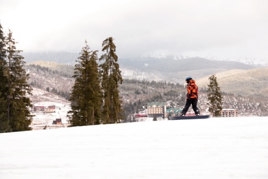 Photo of Snowboarder on slope at resort, space for text. Winter vacation