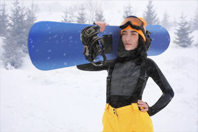 Young woman with snowboard wearing winter sport clothes outdoors