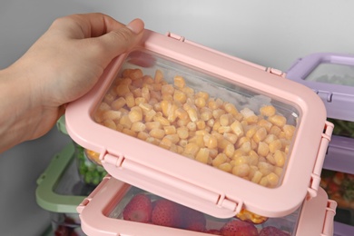 Photo of Woman taking box with corn kernels from refrigerator, closeup