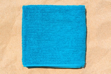 Soft blue beach towel on sand, top view