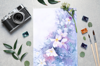 Flat lay composition with watercolor paints and floral picture on grey stone table