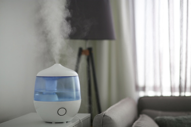 Modern air humidifier on table in living room. Space for text