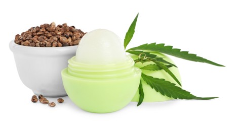 Hemp lip balm, seeds and green leaves on white background. Natural cosmetics