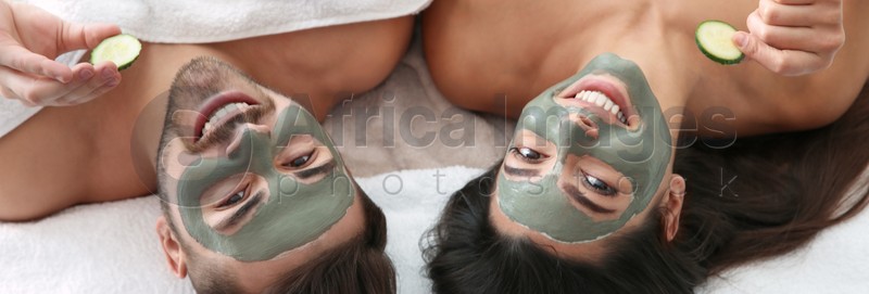 Happy couple enjoying facial treatment procedure in spa salon, above view. Banner design