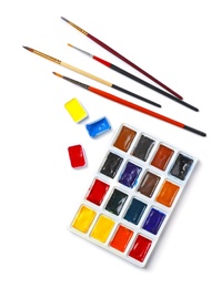 Plastic palette with colorful paints and brushes on light background, top view
