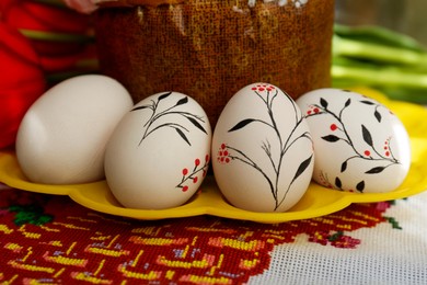 Eggs with floral ornaments and kulich for Easter on table, closeup
