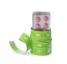 Weight loss pills and measuring tape on white background