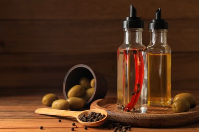 Photo of Different cooking oils and ingredients on wooden table. Space for text