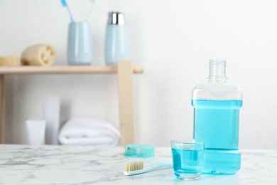 Mouthwash and other oral hygiene products on white marble table in bathroom, space for text