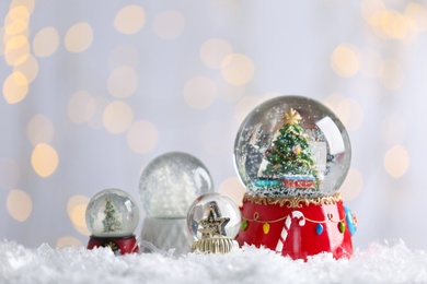 Beautiful snow globes against blurred Christmas lights