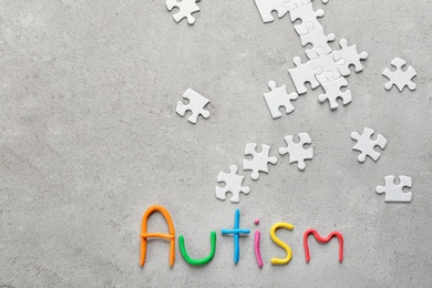 Word "Autism" and puzzle pieces on light background, flat lay