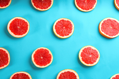 Tasty ripe grapefruit slices on blue background, flat lay