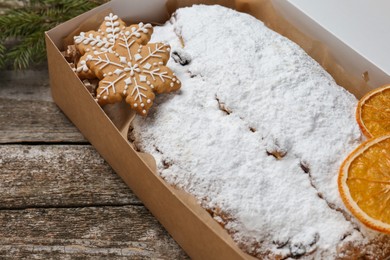 Traditional Christmas Stollen in cardboard box on wooden table, closeup