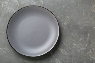 Empty ceramic plate on grey table, top view. Space for text