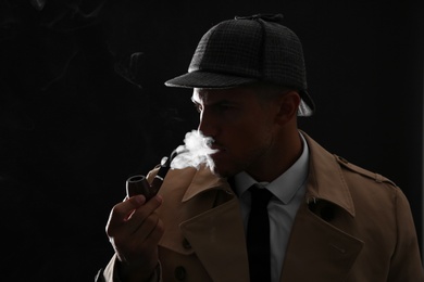 Old fashioned detective smoking pipe on dark background