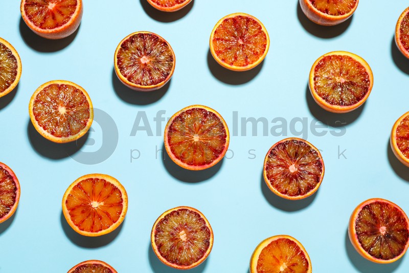 Many ripe sicilian oranges on light blue background, flat lay