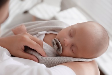 Mother holding her cute sleeping baby with pacifier, above view