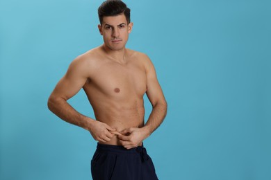 Fit man with marks on body against light blue background, space for text. Weight loss surgery