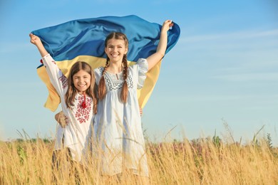 Happy girls with national flag of Ukraine in field. Space for text