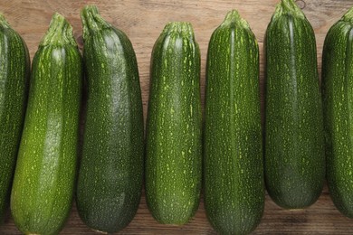 Raw ripe zucchinis on wooden table, flat lay