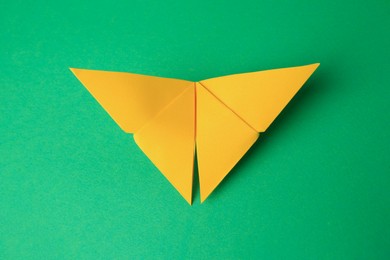 Photo of Origami art. Paper butterfly on green background, top view
