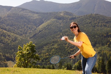 Woman playing badminton in mountains on sunny day. Space for text