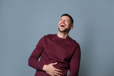 Handsome man laughing on grey background. Funny joke