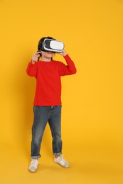 Little girl using virtual reality headset on yellow background