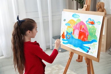 Little child painting picture using easel at home