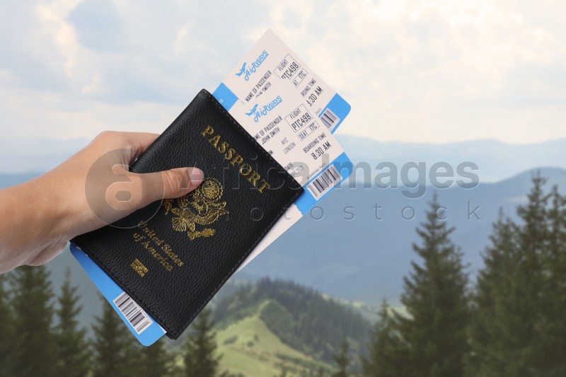 Woman holding passport with tickets in mountains, closeup. Travel agency service