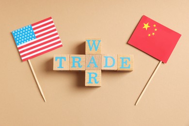 Wooden cubes with words Trade War, American and Chinese flags on beige background, flat lay