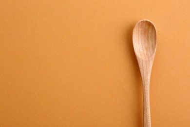 Clean wooden spoon and space for text on color background, top view