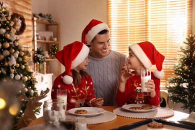 Happy father and his children eating delicious Christmas cookies at home