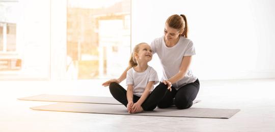 Mother and daughter doing yoga together at home. Banner design