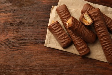 Photo of Sweet tasty chocolate bars with caramel on wooden table, top view. Space for text