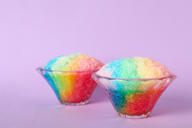 Rainbow shaving ice in glass dessert bowls on violet background