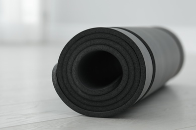 Rolled yoga mat on wooden floor, closeup