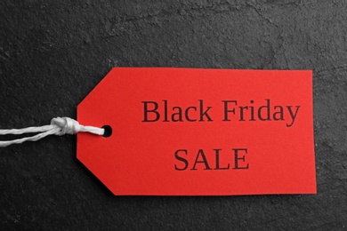 Red tag with words BLACK FRIDAY SALE on dark slate background, top view