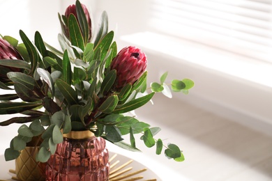 Photo of Vase with bouquet of beautiful Protea flowers on table indoors