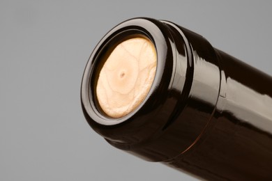 Photo of Wine bottle with cork on grey background, closeup. Space for text