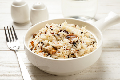 Delicious rice pilaf with mushrooms on white wooden table