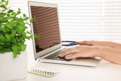 Photo of Doctor working on laptop at desk in clinic, closeup. Online medicine concept