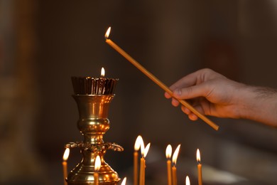Man lighting candle near stand in church, closeup. Baptism ceremony
