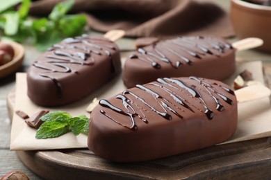 Delicious glazed ice cream bars and mint on wooden board, closeup