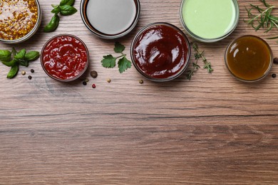 Many different sauces on wooden table, flat lay. Space for text