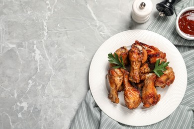 Plate with delicious fried chicken wings on light gray marble table, top view. Space for text